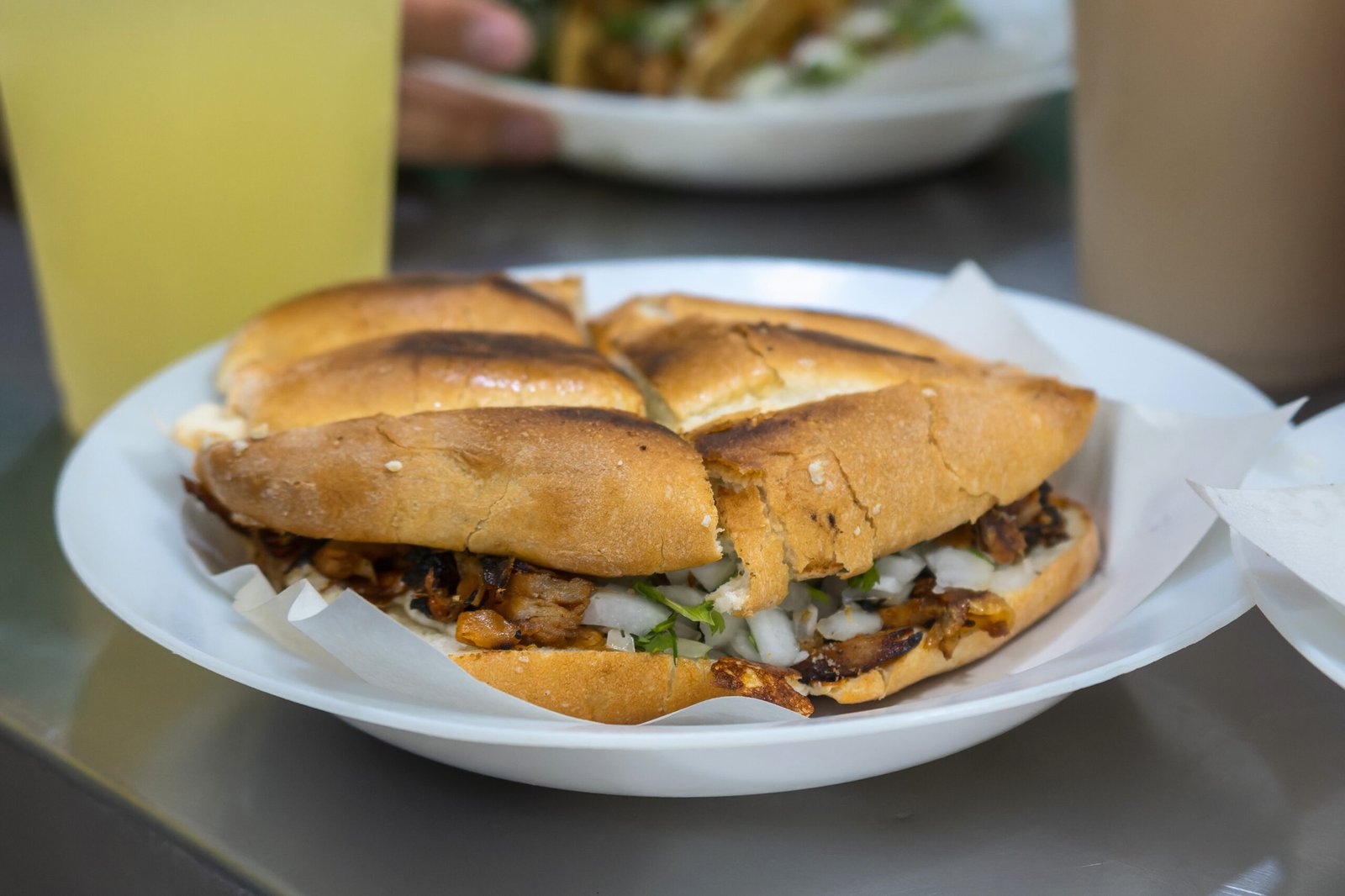 Close-up of a delicious Mexican Torta de Carne de Pastor sandwich, featuring seasoned pork, fresh onions, and cilantro, perfectly nestled in a toasted bun. Mexican cuisine, street food, authentic flavors.