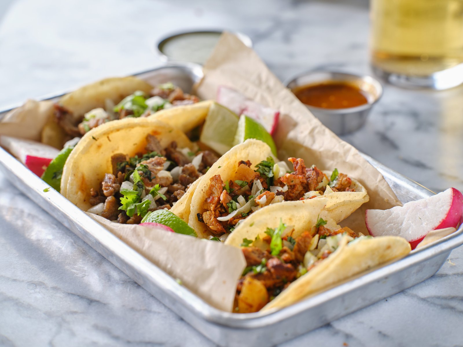 platter of mexican street tacos with carne asada, chorizo, and al pastor in corn tortillas