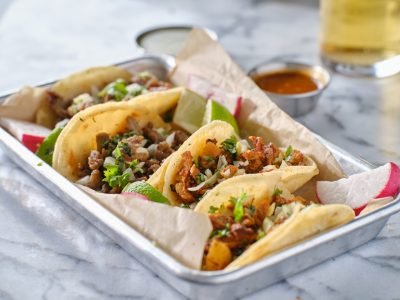 platter of mexican street tacos with carne asada, chorizo, and al pastor in corn tortillas